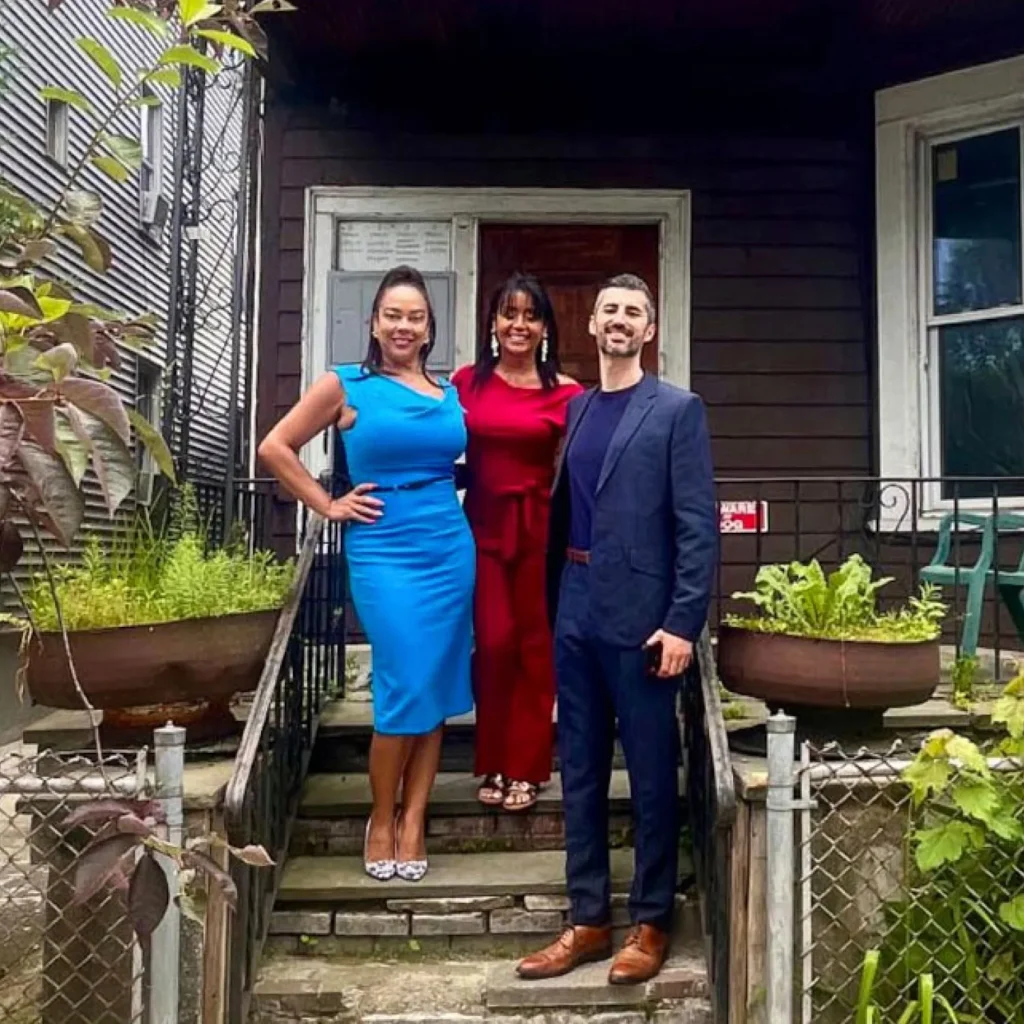 La Colaborativa leadership team members standing in front of a house